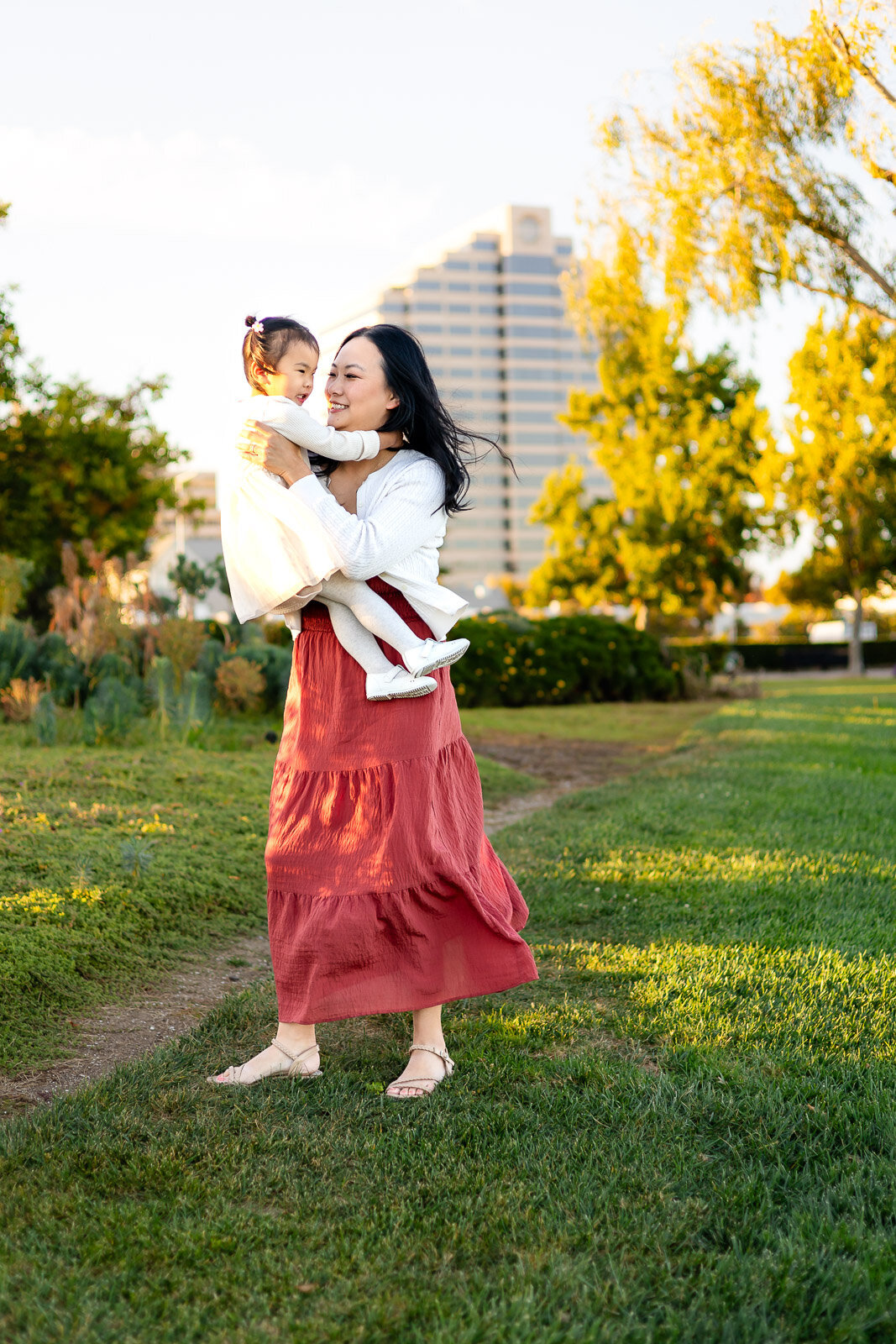 Mother lifting daughter with laughter in a sunny San Francisco park – Bay Area Family Portfolio – Ellobelle Photography
