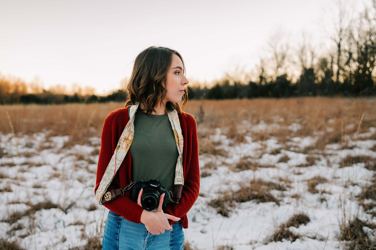 senior pictures in Branson Missouri of high school senior holding camera in the snow