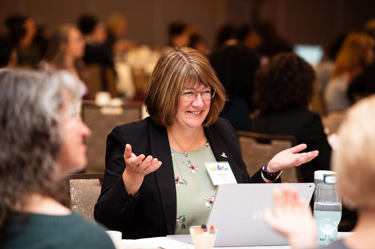 a woman with her hands open and palms up as she speaks with attendees during a 2-day corporate conference at the Westin Hotel.  Captured by Ottawa Event Photographer JEMMAN Photography COMMERCIAL