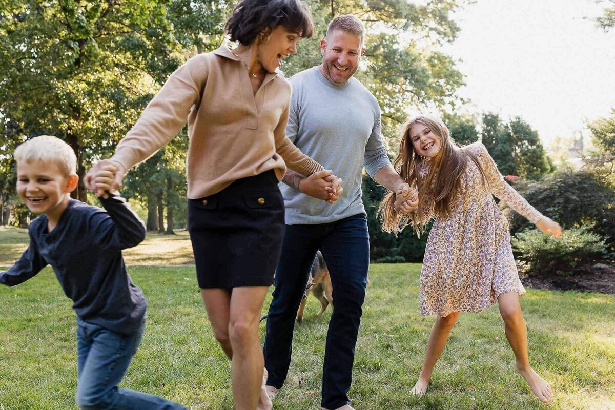 A family running hand in hand on a sunny day, capturing joyful moments in Cleveland. Relaxed and candid family photography style.