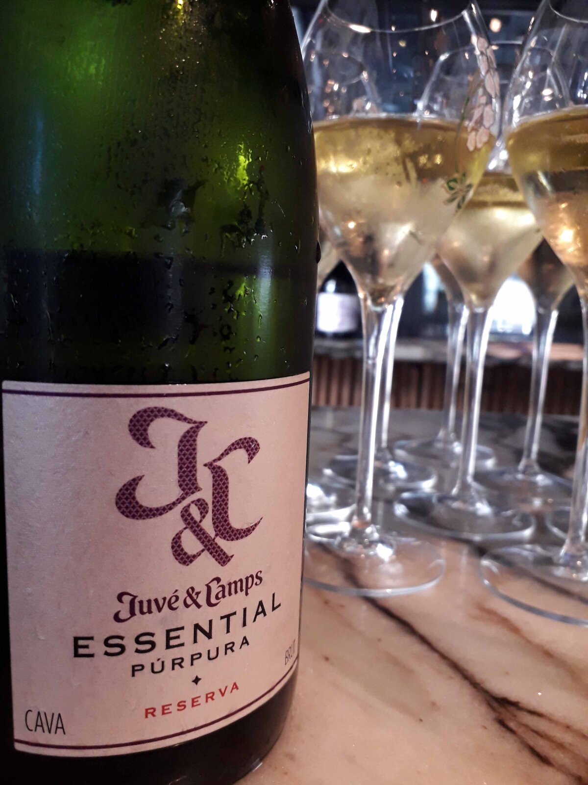 A bottle of wine in the foreground and glasses filled with white wine beside it.