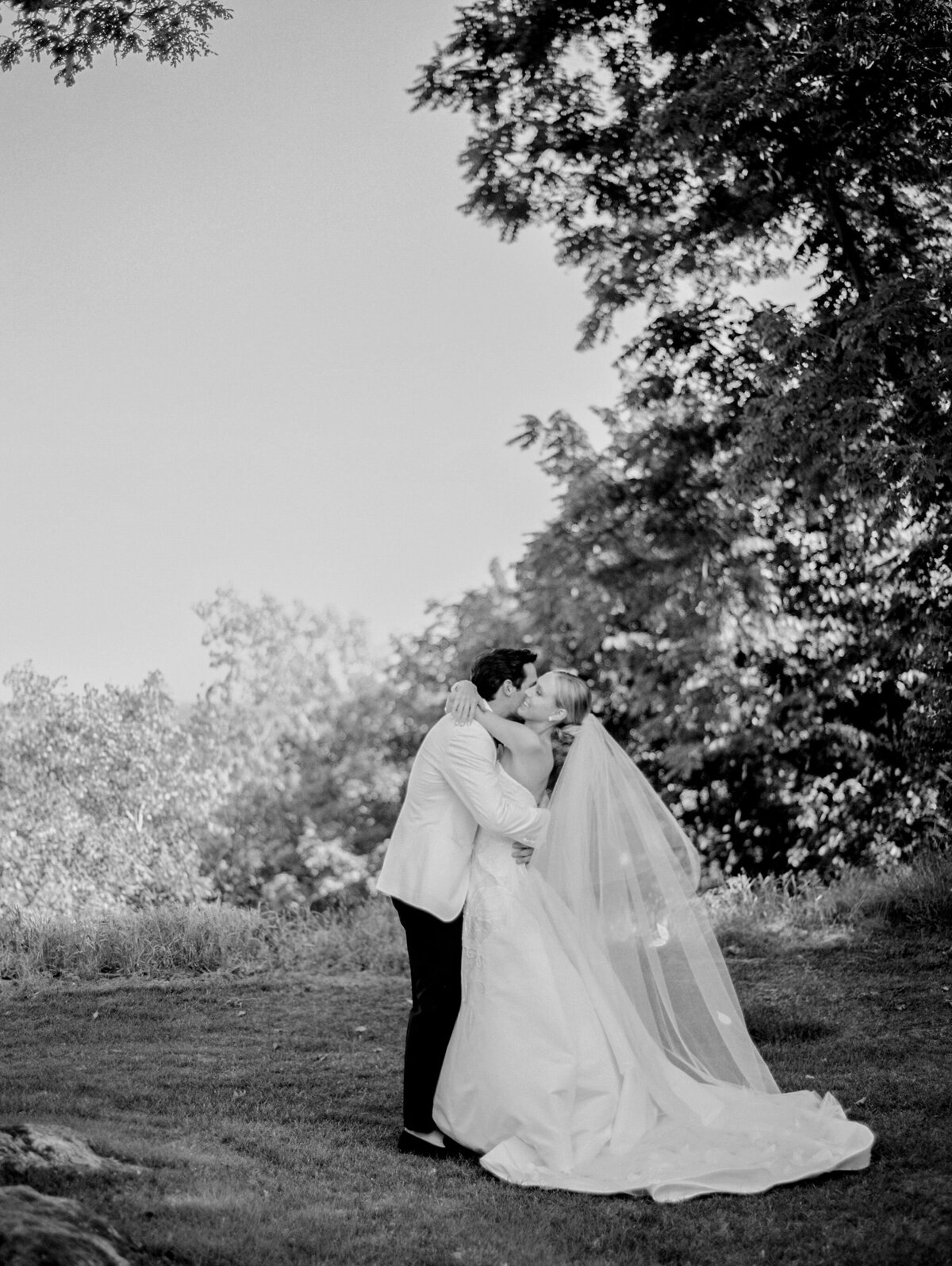 Black and white photo of the bride and groom sharing a hug outside. 