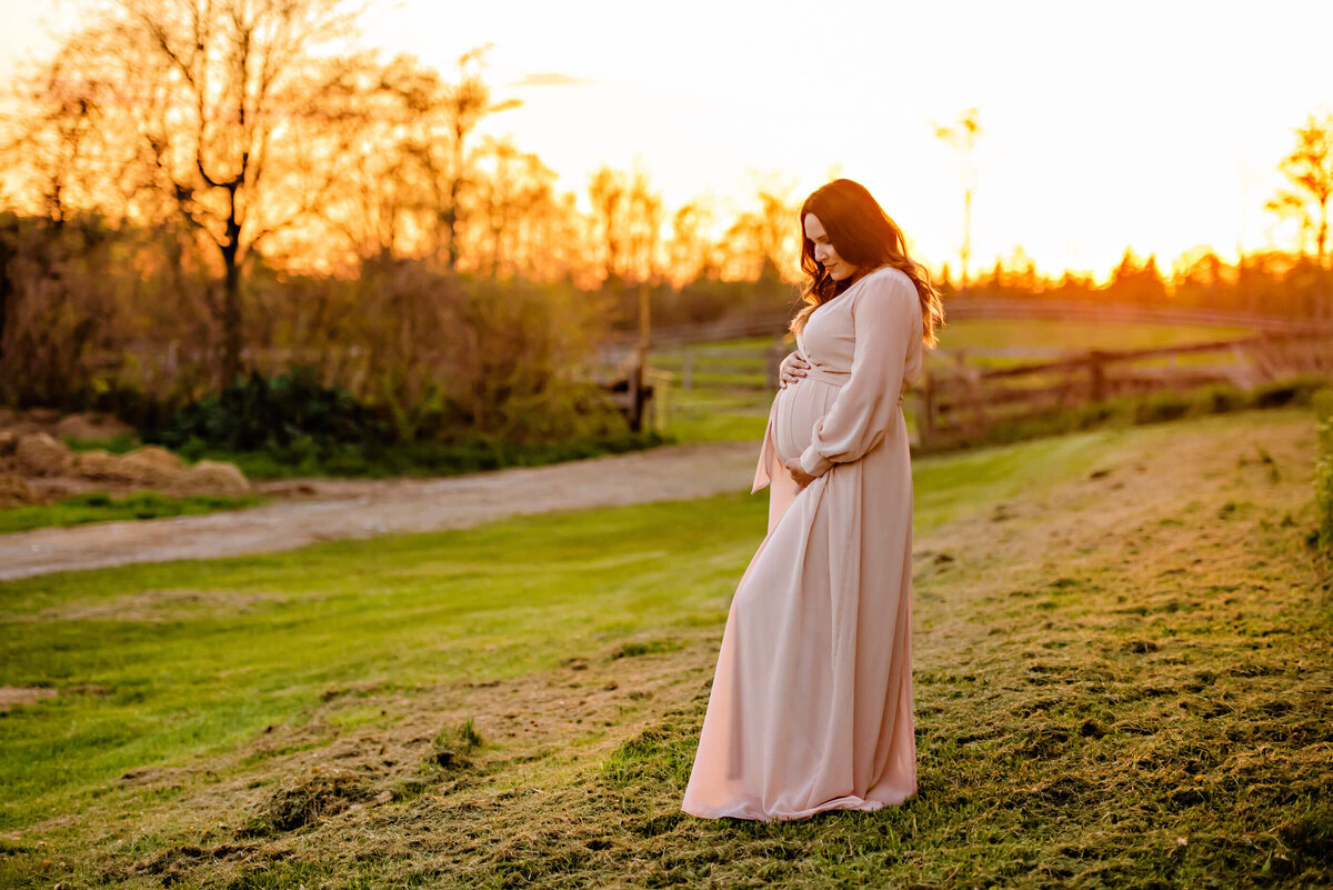 regnant woman standing on a hill in the golden hour for her outdoor maternity photography session in Burlington, On