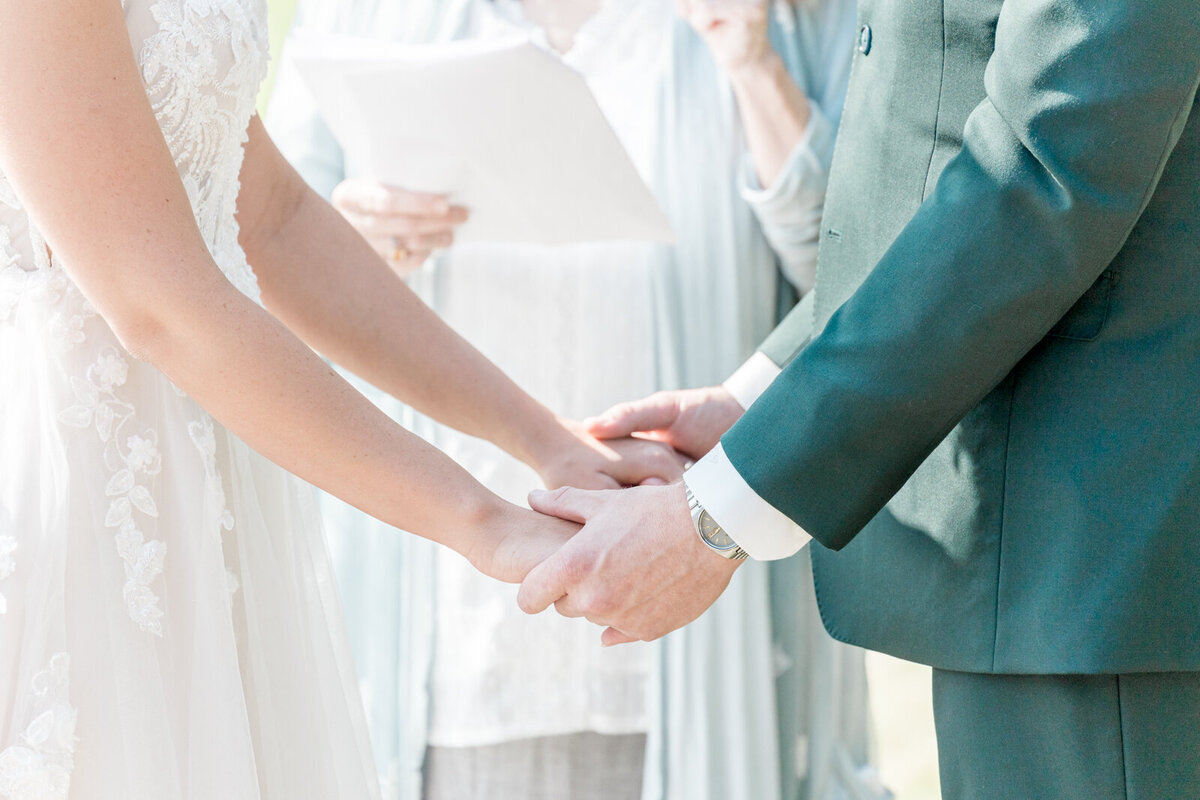 A bride and groom hold hands during their ceremony