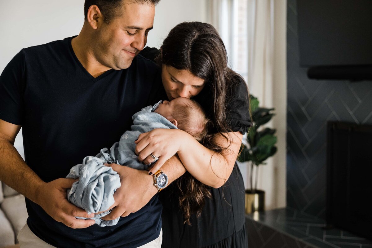 A couple sharing a tender moment with their baby during an at-home newborn photography session.