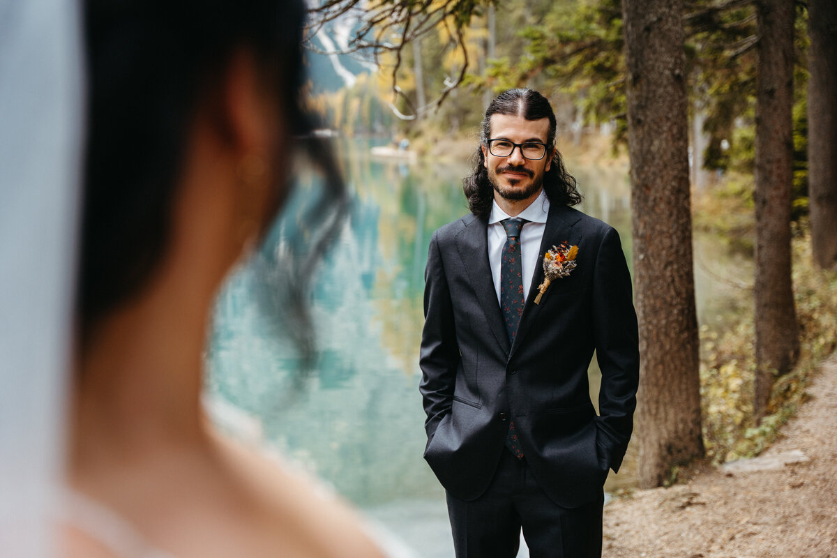 Groom smiling at bride in forest near lake