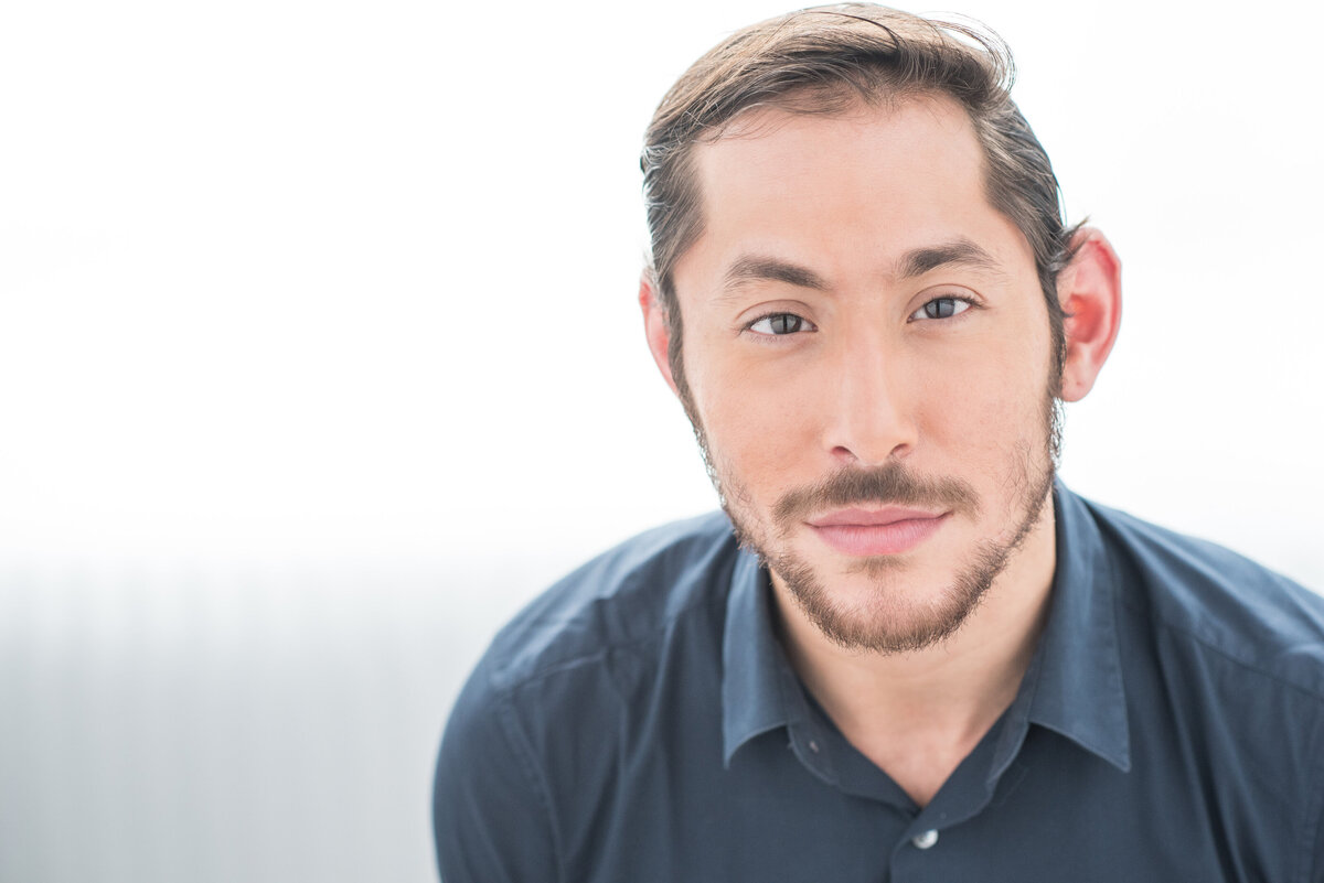 A man in a button up shirt with a slight smile on his face.