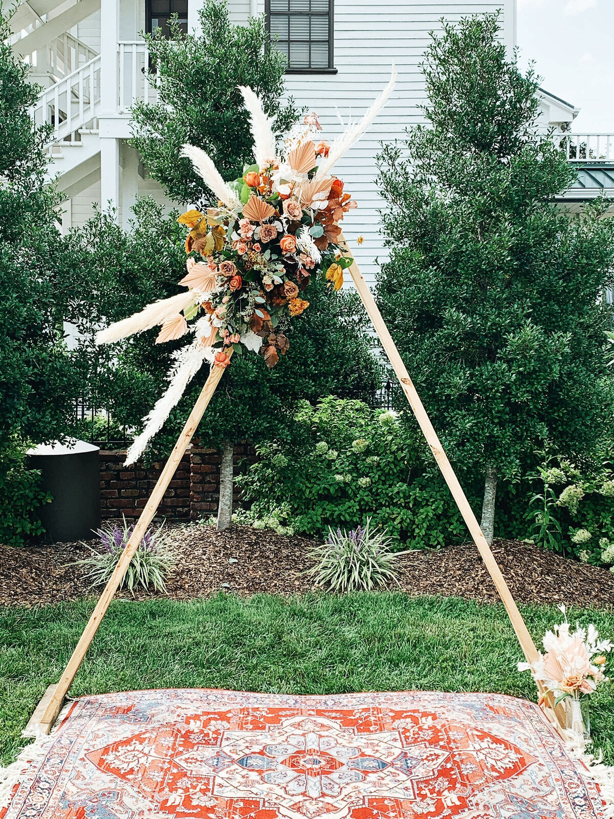 Triangle arbor with arrangement with pampas grass and organic florals in tones of terracotta