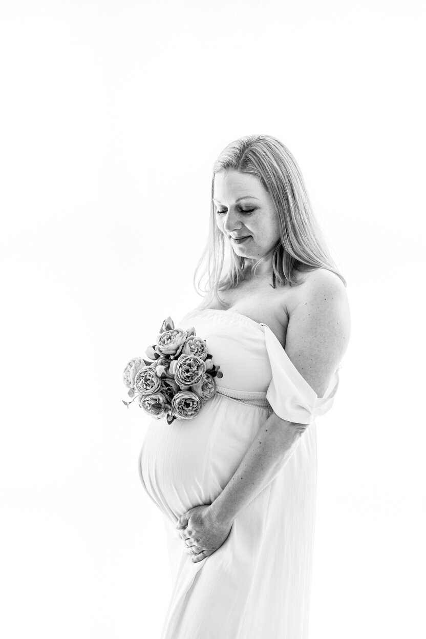 Sort/hvitt bilde av gravid kvinne i hvit kjole, fotografert av Fotograf Linn Landmark i Studio Landmark, Bergen.