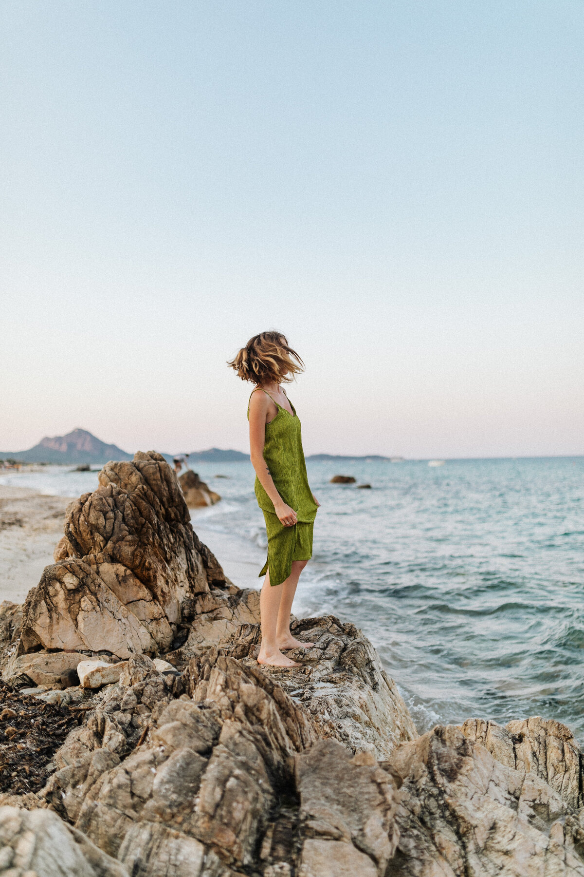 kaboompics_a-woman-in-a-green-dress-on-a-rock-by-the-sea-18068