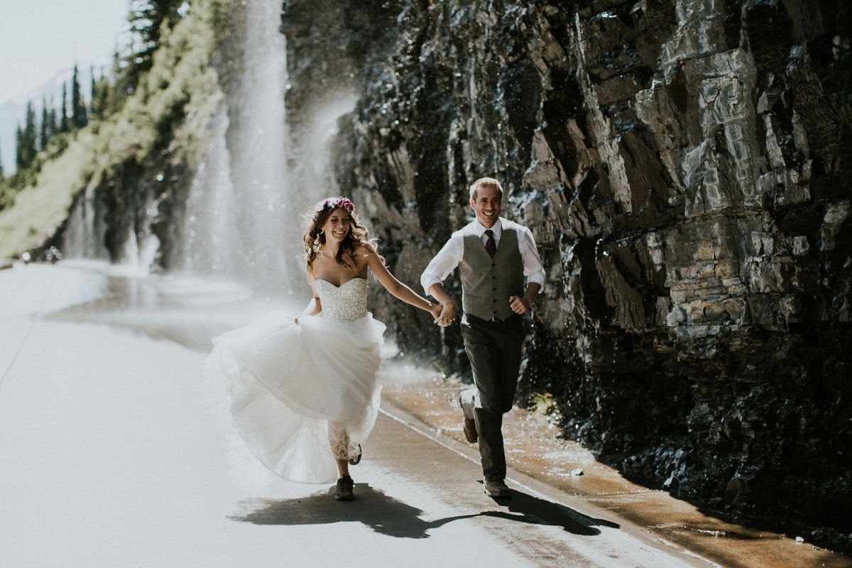 Glacier National Park Weeping Wall Elopement Couple Running under Waterfall