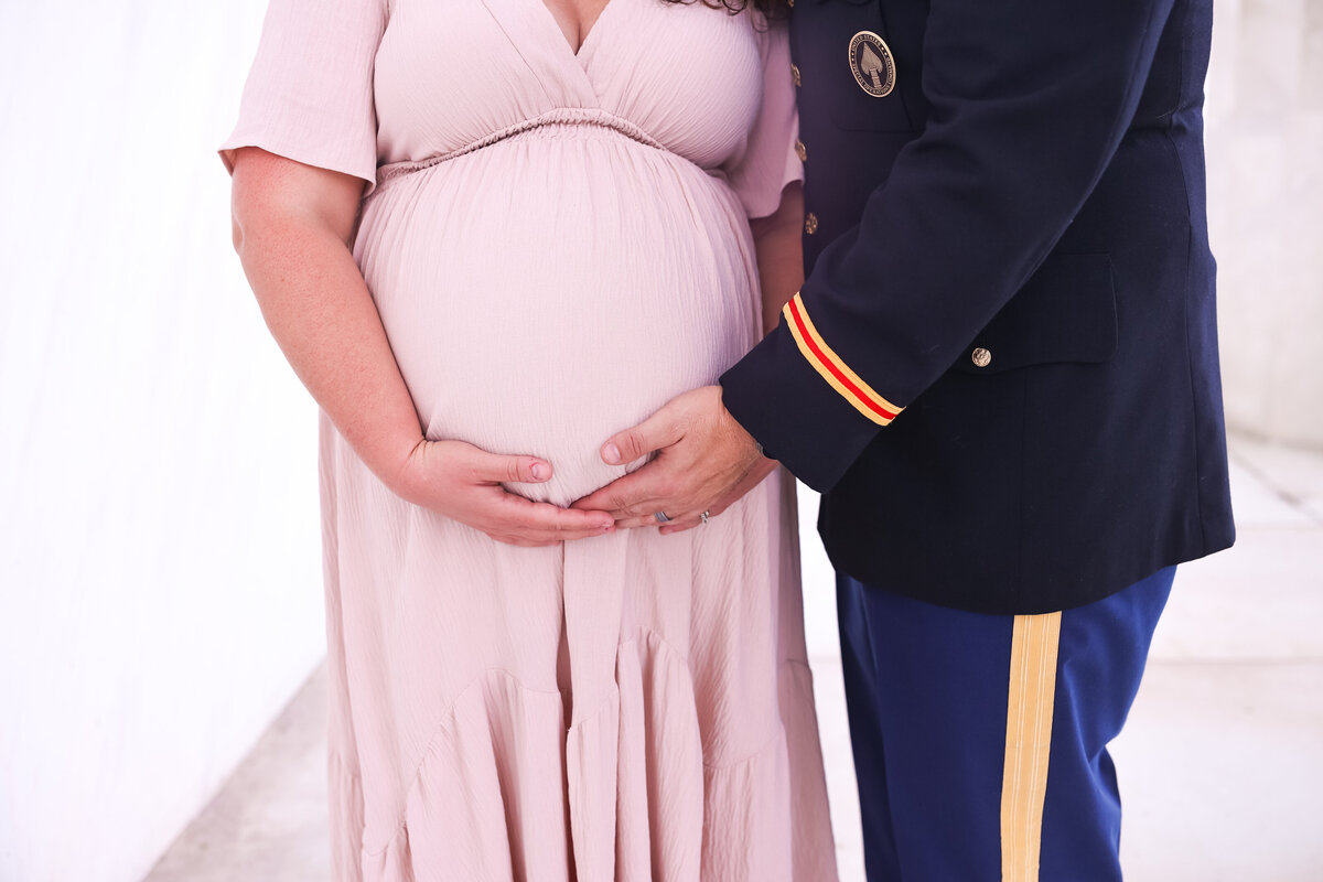 pregnant woman and husband hold belly in Fort Moore Georgia by family photographer Amanda Richardson Photography