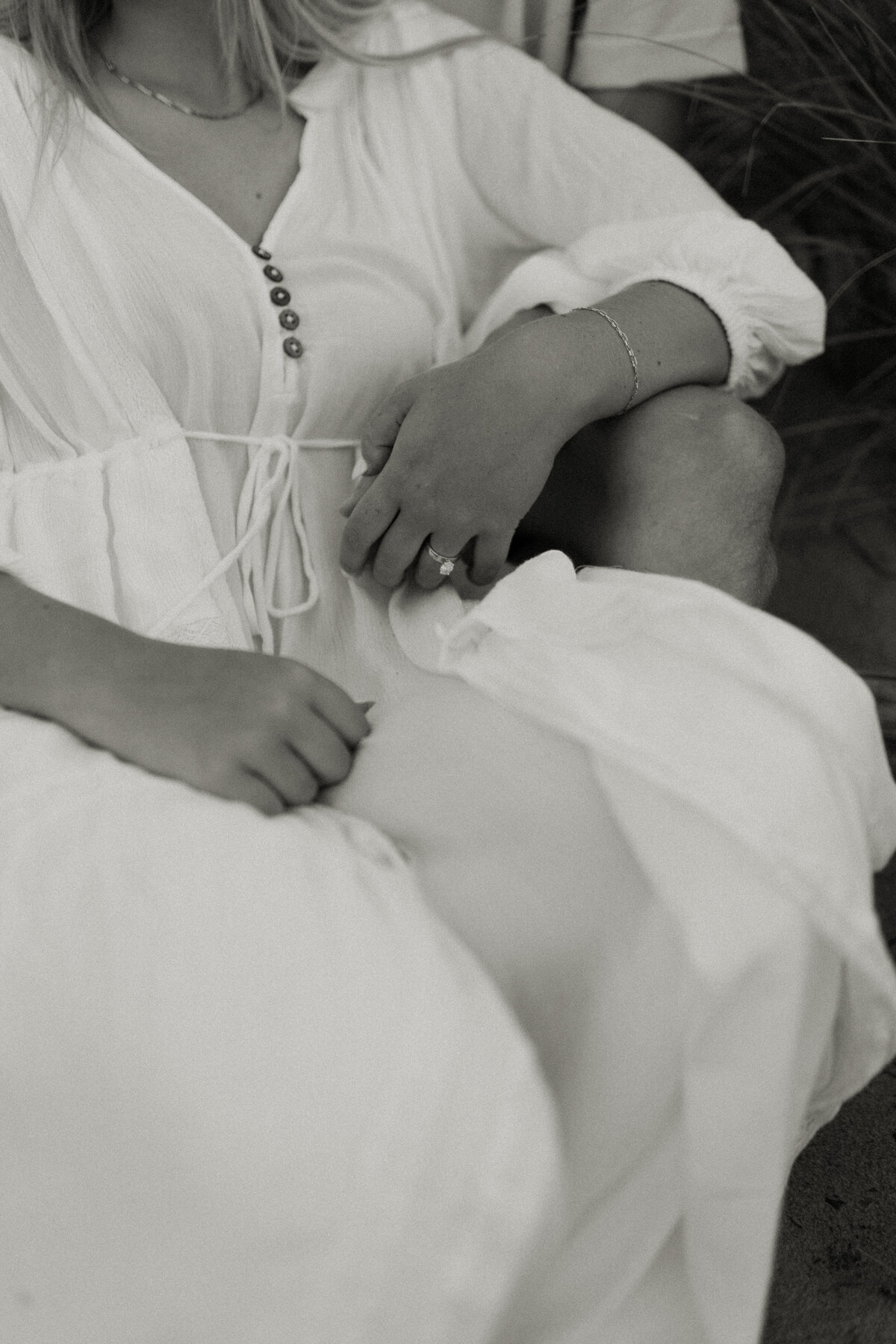 Bride to be rests her arm on her fiancé's knee during a Lake Superior engagement session in Duluth.