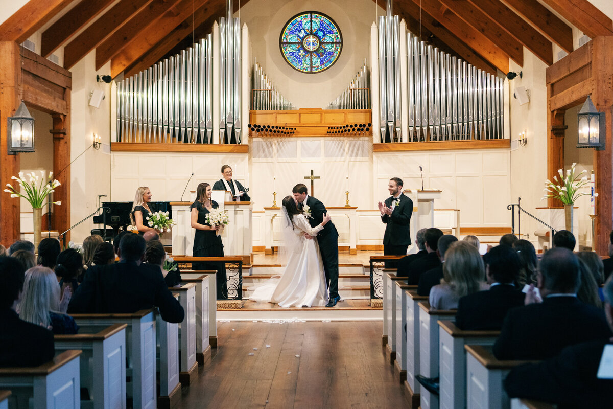 a bride and groom sharing a kiss in a church during their wedding ceremony