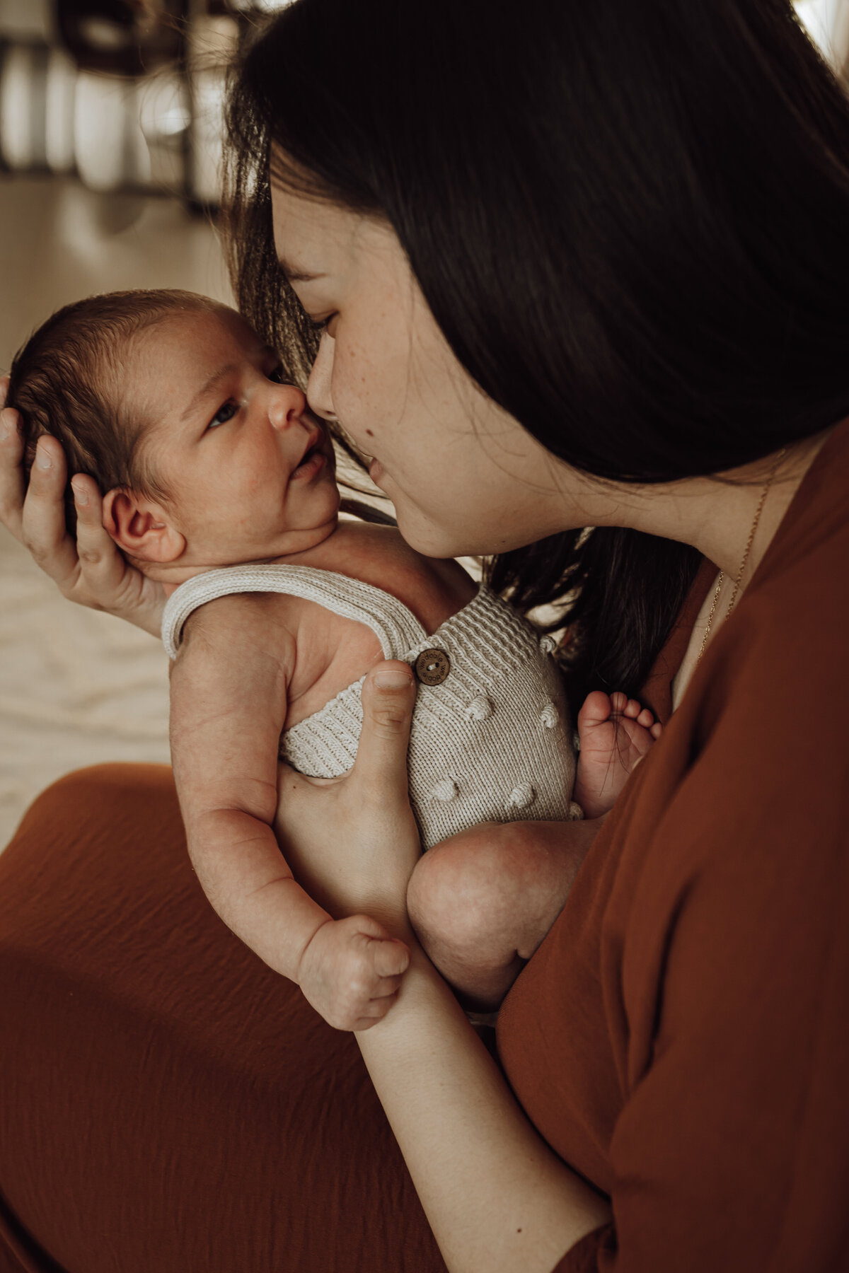 Mama geeft newborn baby een kus tijdens newborn fotoshoot