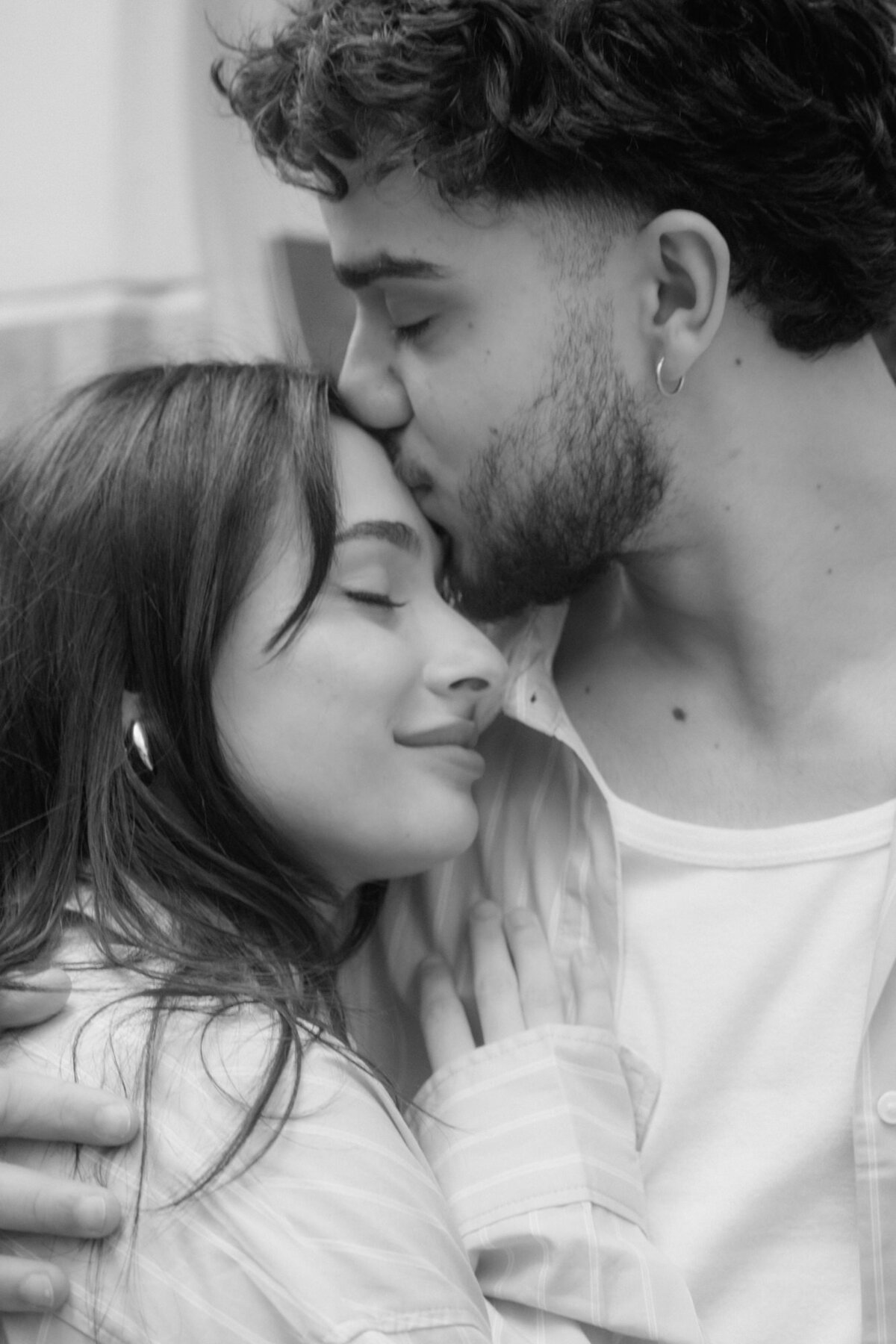 While kissing his girl on the forehad, the man holds her tight.