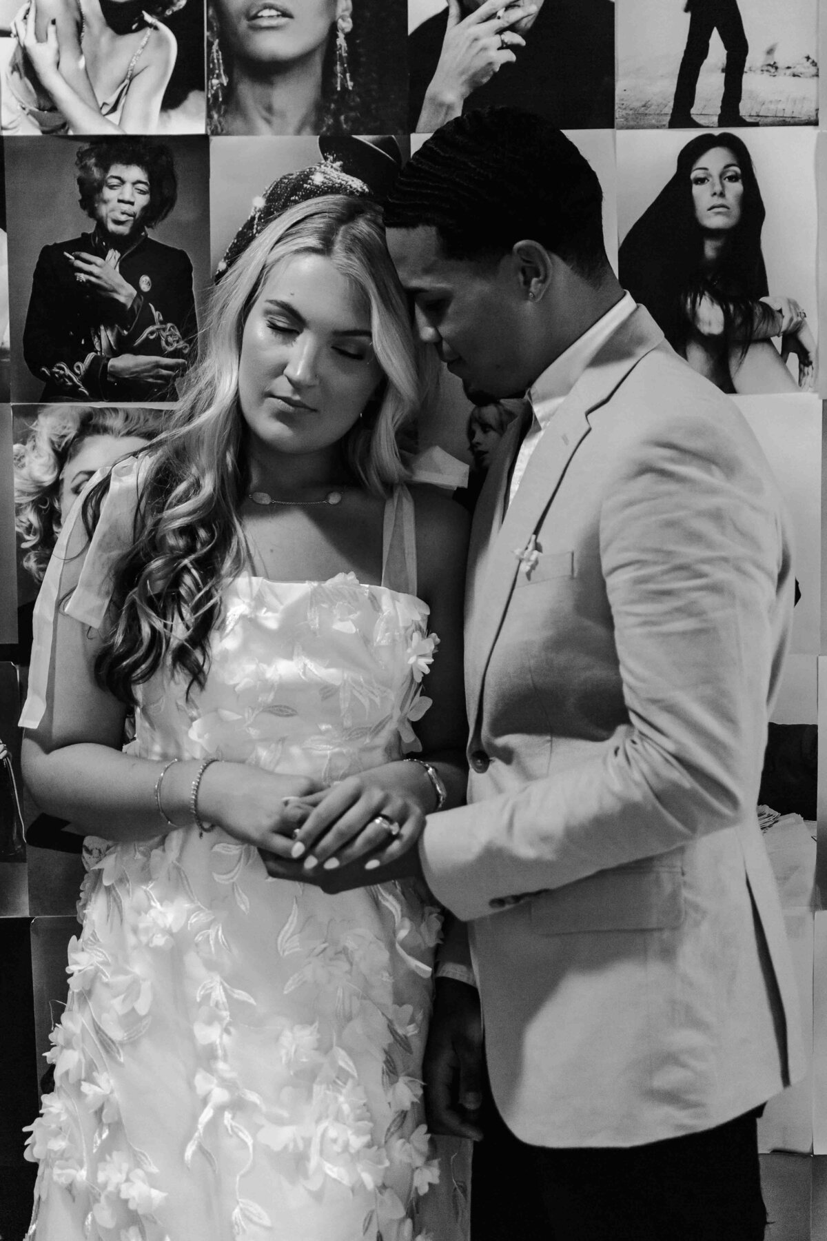 bride and groom in front of wall of pictures in black and white