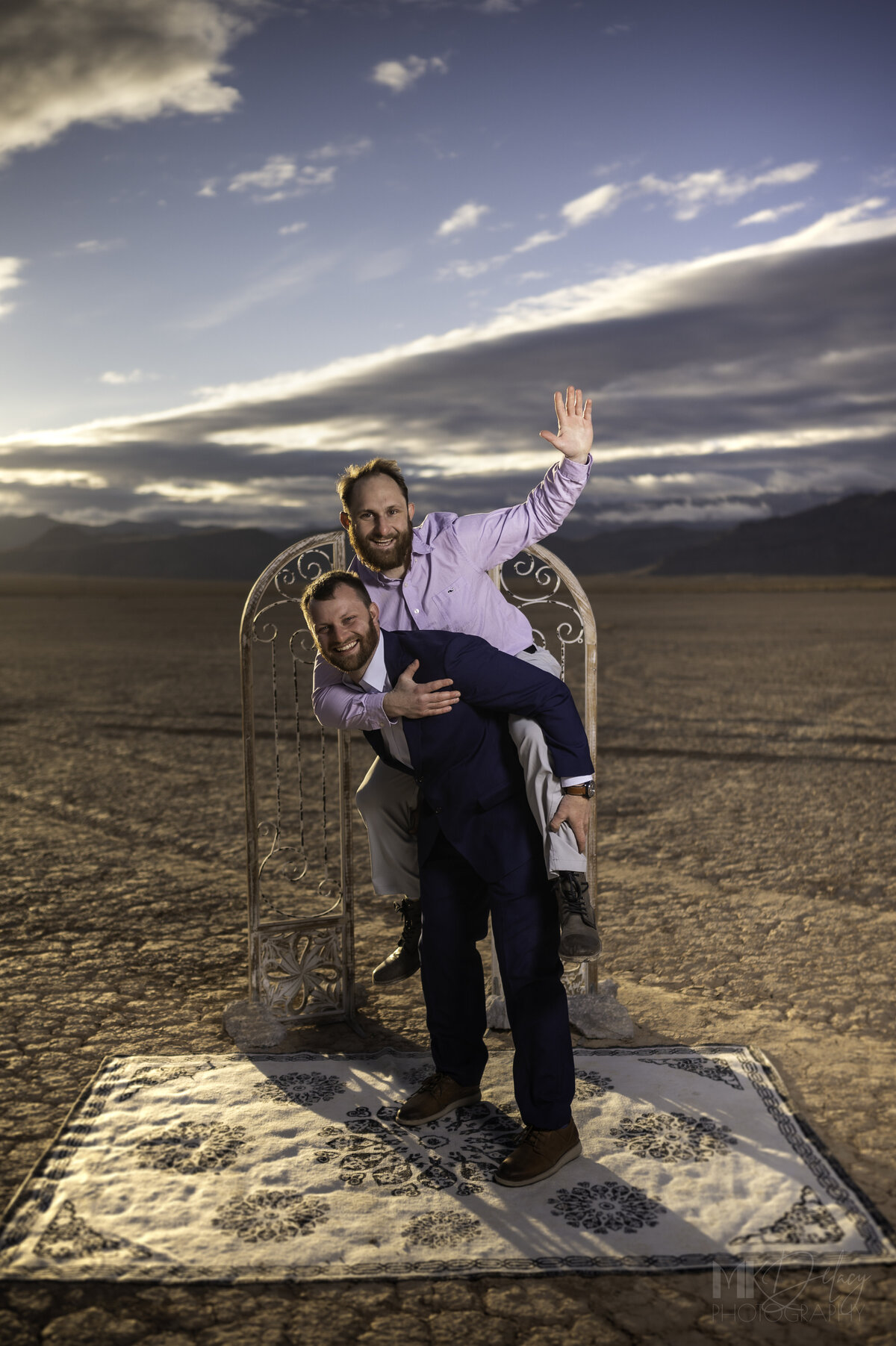 Best man Brother on Grooms back brother  Dry lake Bed elopement Blue Suit on Groom  flowers by michelle  bride in cream color wedding dress with deep  plunging  neckline mountain skyline  sunset las vegas wedding photographers mk delacy photography