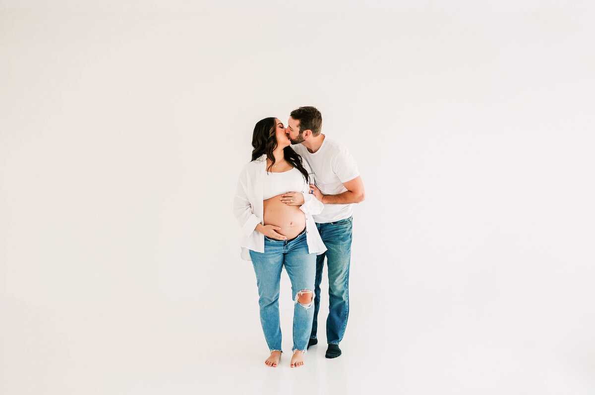 Springfield Mo matenrity photographer captures prengnat couple in jeans kissing in studio