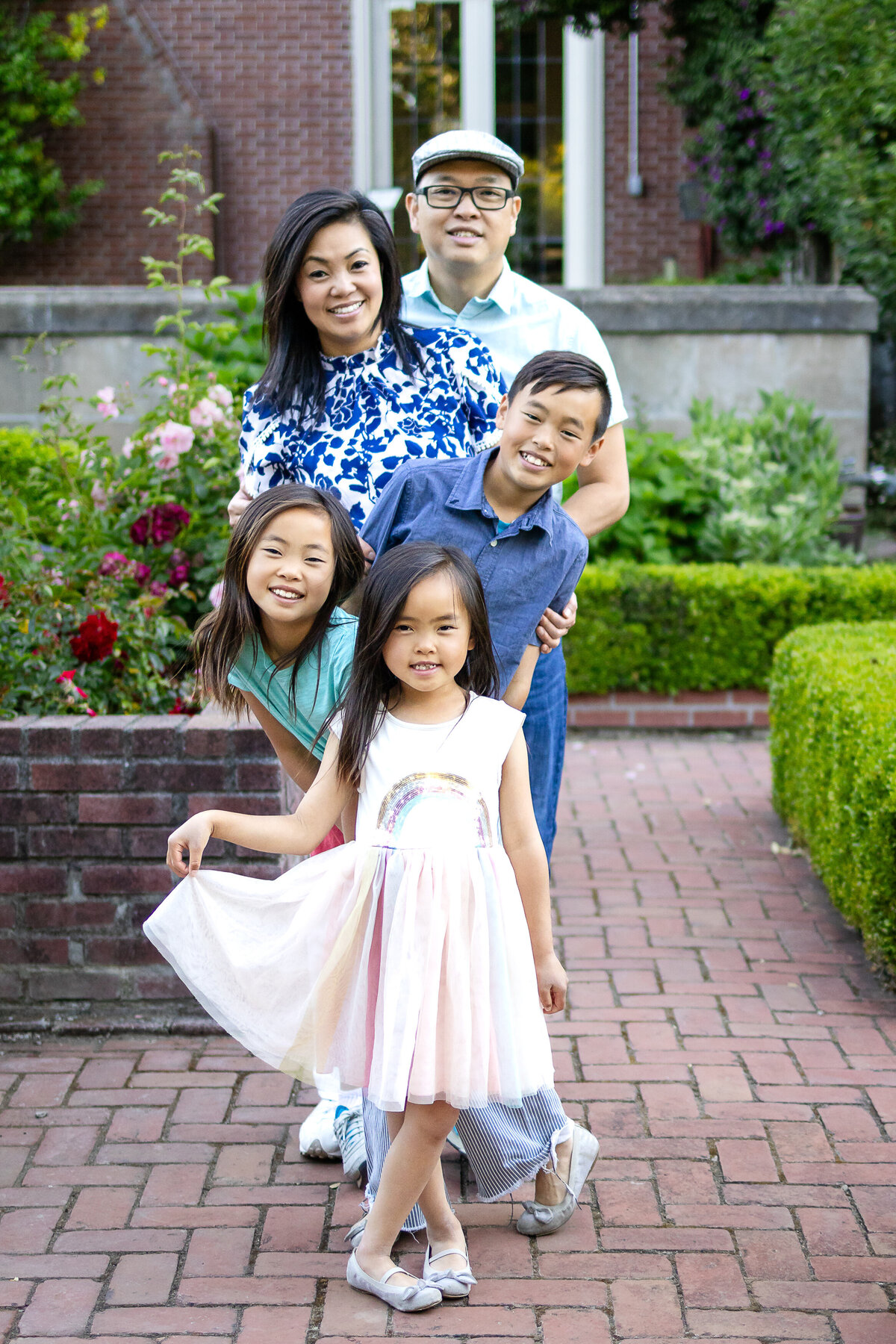 Golden hour portrait of a family of five standing in rose garden – joyful, natural light family photography by Ellobelle Photography in the San Francisco Peninsula kohl mansion Burlingame