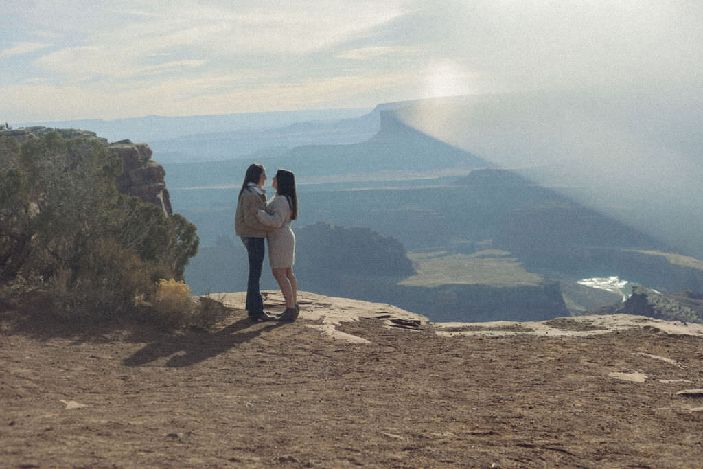 A couple standing close together on a canyon overlook.