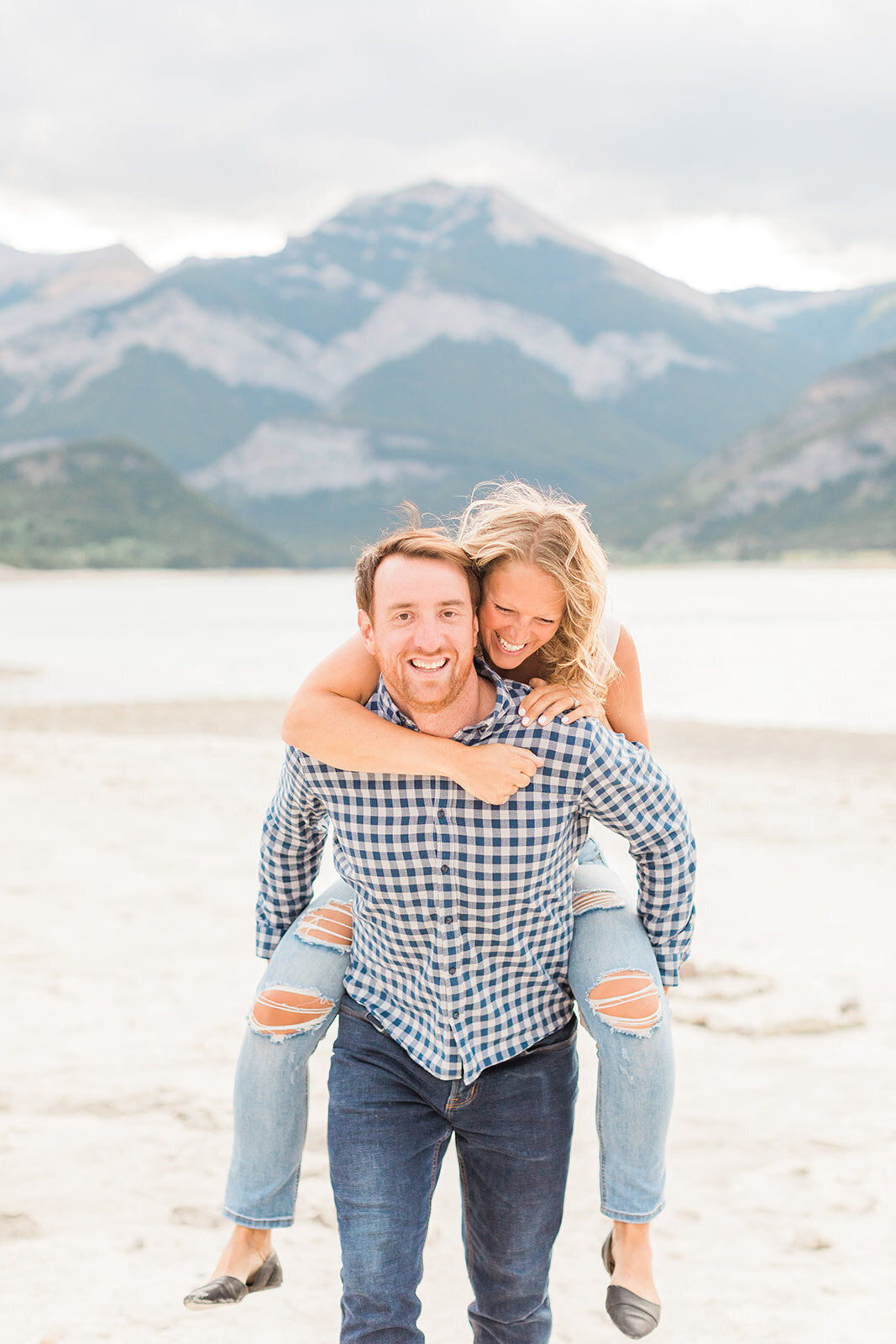 Man giving a woman a piggy-back as she laughs in the mountains near Calgary, AB