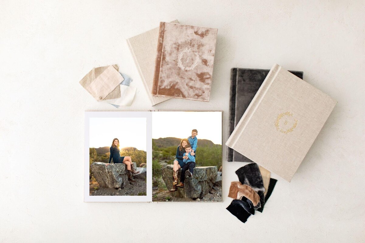 8x10 album surrounded by others8x10 album open with maternity portraits by Cactus & Pine Photography, surrounded by other albums and swatches on white tabletop
