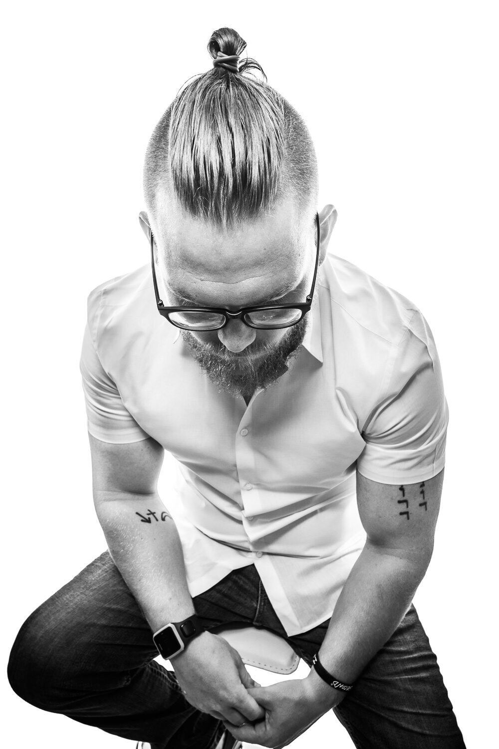 Artistic branding portrait of a man sitting with his head bowed on a white backdrop, captured in a stylized 3D studio setup.