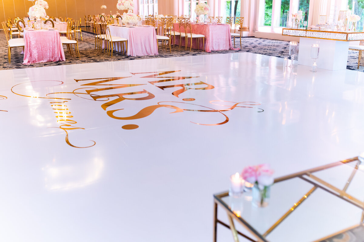 a white dance floor at a wedding  reception with Mr. and Mrs. written on it in gold lettering