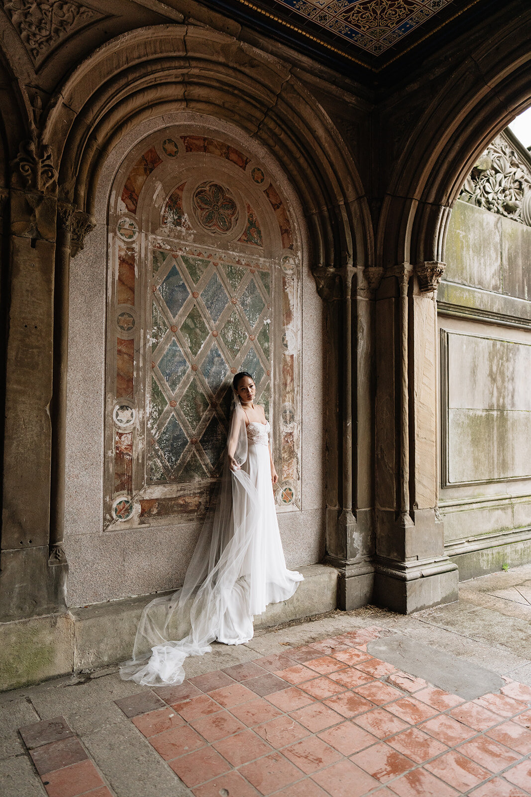 Bride standing beneath ornate arches at Bethesda Terrace in New York City — editorial wedding portrait inspired by timeless architecture.
