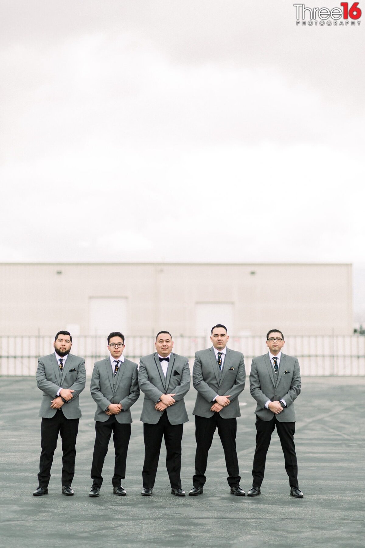 Groom and Groomsmen pose together with hands over wrists in a sign of unity and friendship