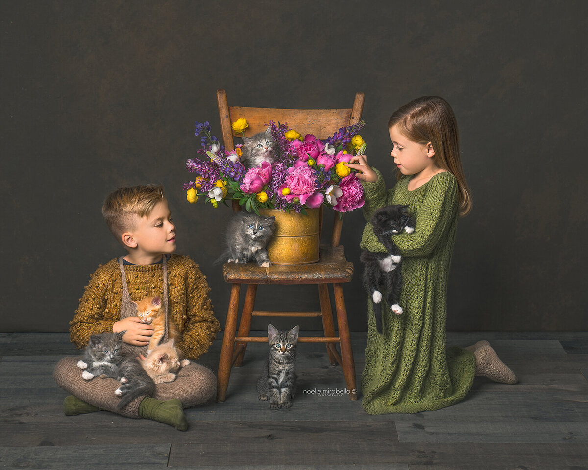 Children playing with kittens next to a chair holding flowers.