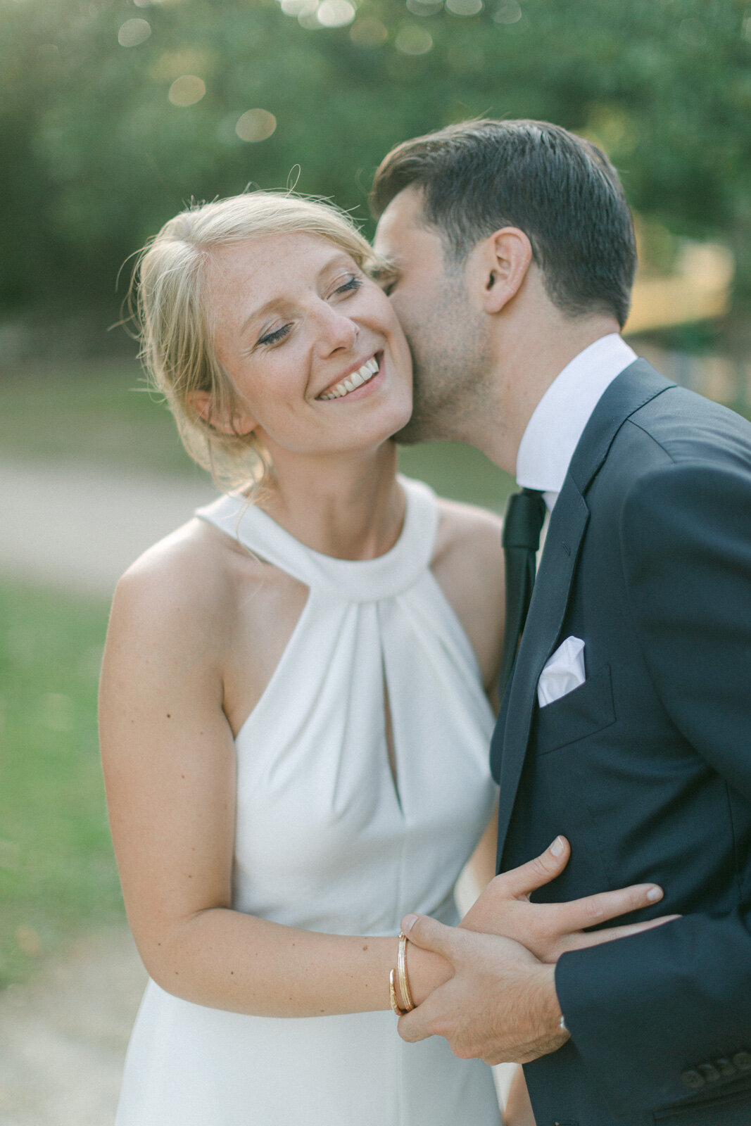 Marié embrassant sa femme sur la joue lors d’un mariage en extérieur à Nantes, instant joyeux et romantique.