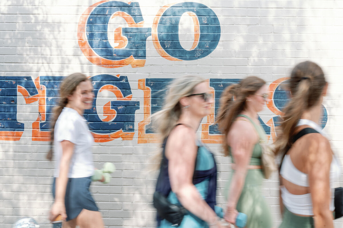 Women smiling and walking by an Auburn mural