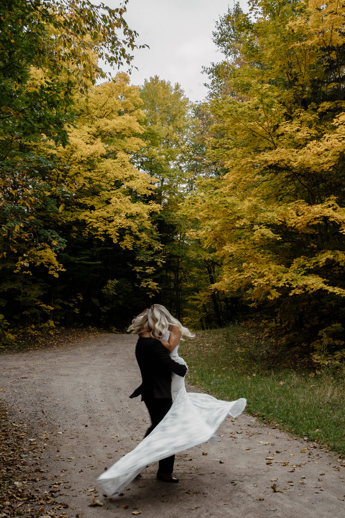 bride and groom spinning on trail in woods