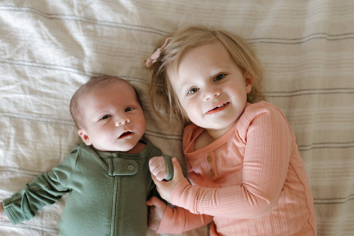 Longmont siblings sitting on bed during in home newborn session