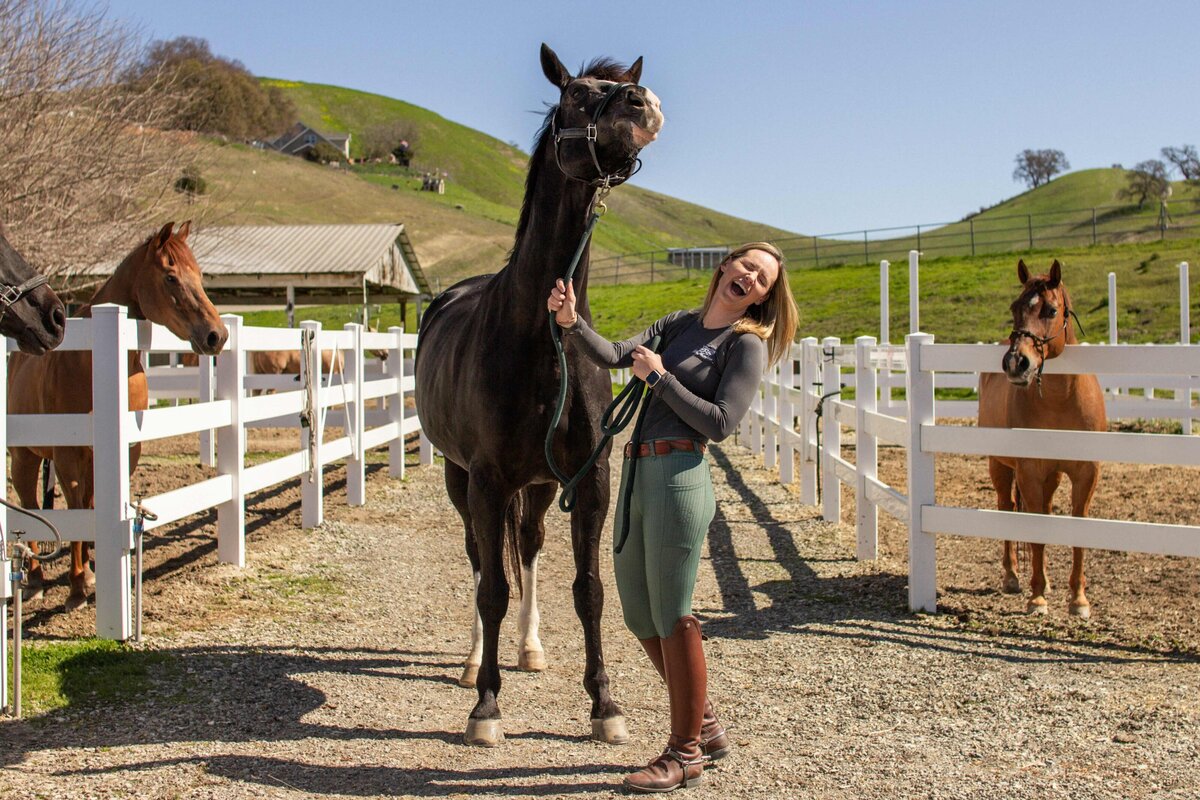 Sam laughing while a  grand prix horse playfully tosses it's head