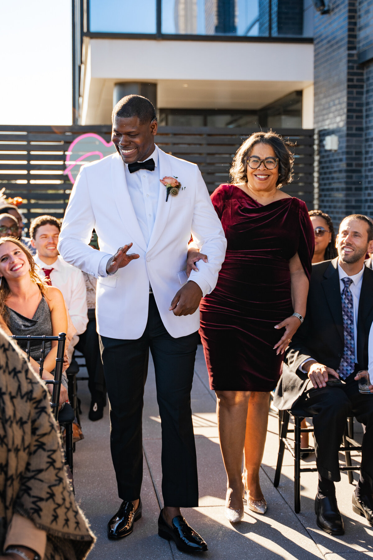 Groom waves and walks with his mother down the aisle at his wedding at The Terrace in Columbus, Ohio.