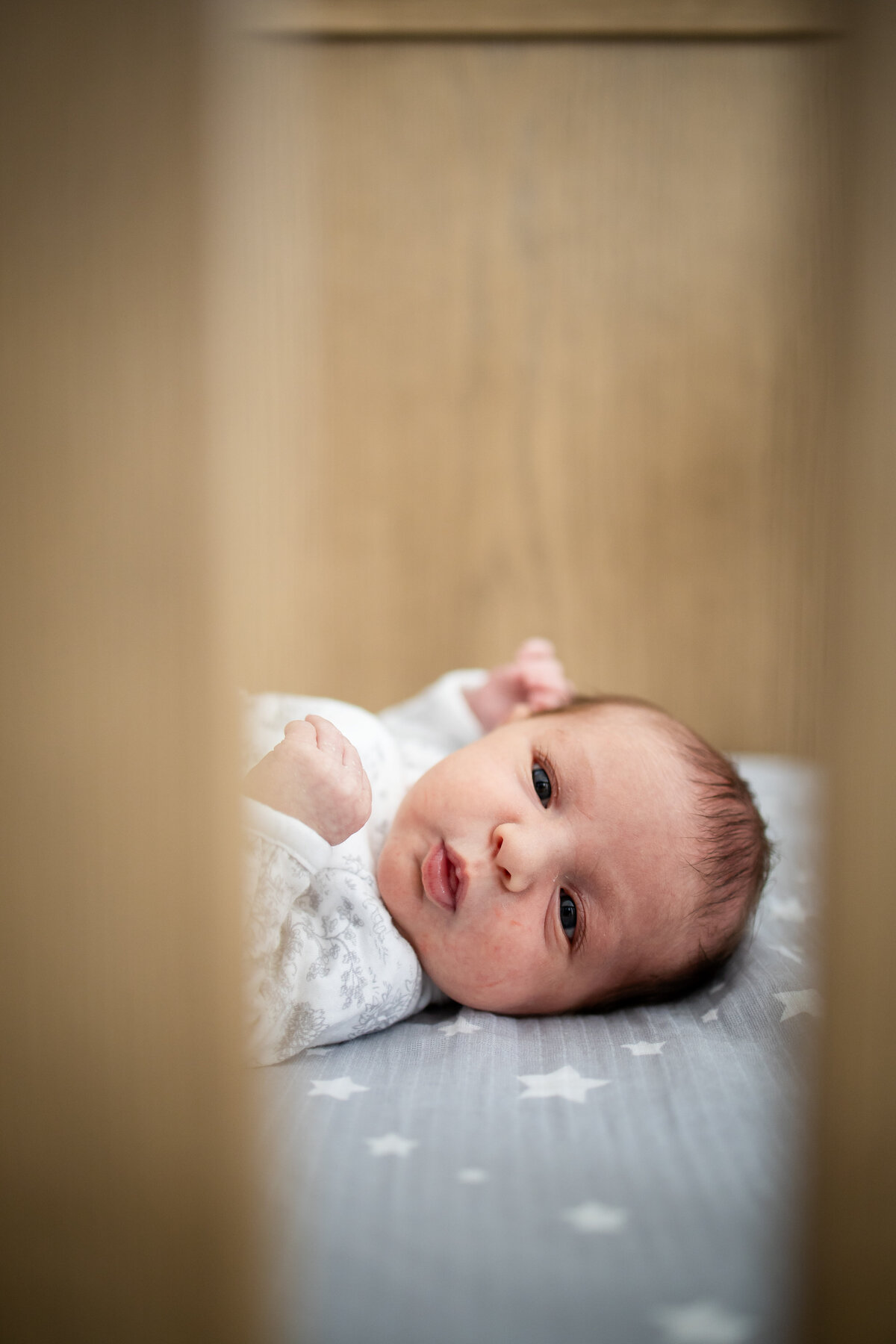 Peeking at newborn baby through crib slats