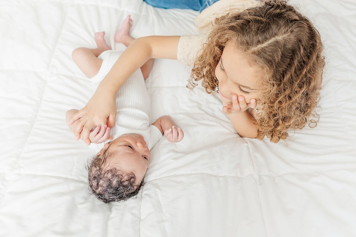 brothers on bed during in home newborn photo session with Sara S iderman PHotography