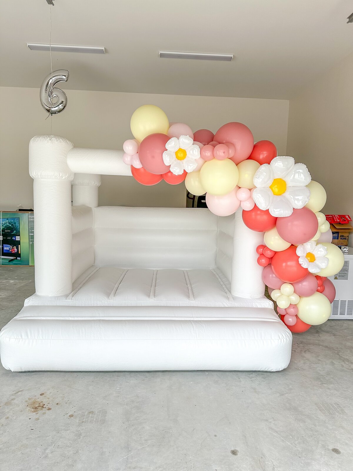 white bounce house with balloons and flowers