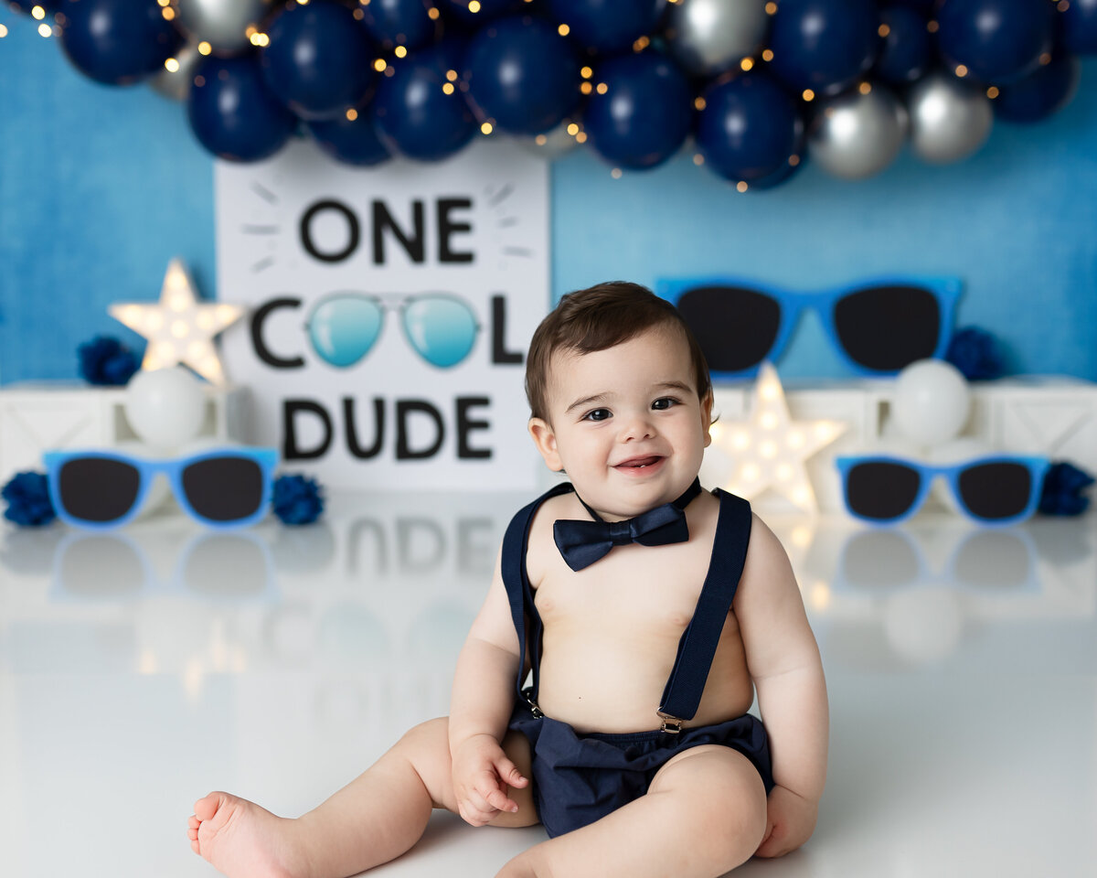 One year old Tampa baby enjoying a personalized luxury cake smash session with one cool dude decorations
