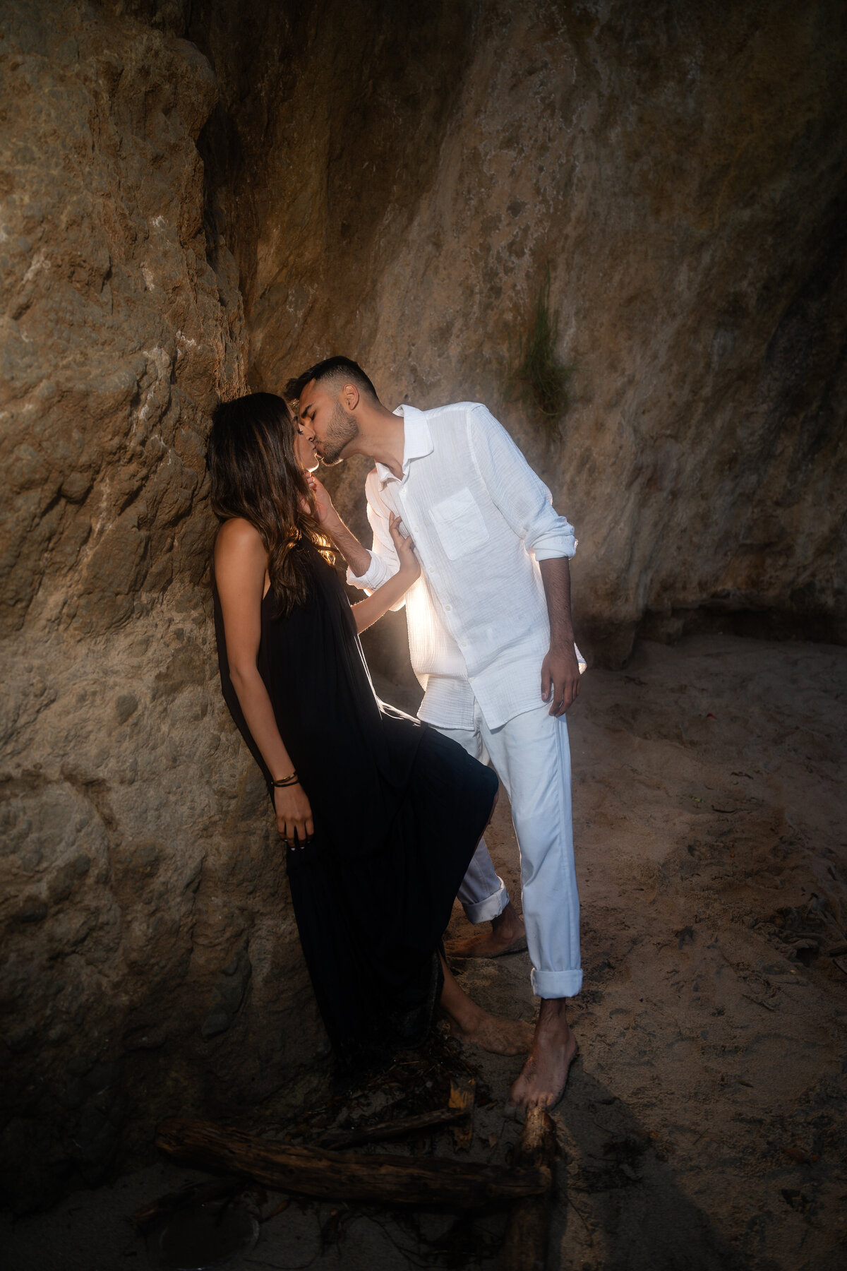 Indian couple eloping at El Matador State Beach in Malibu during sunset kissing against cliff rocks.