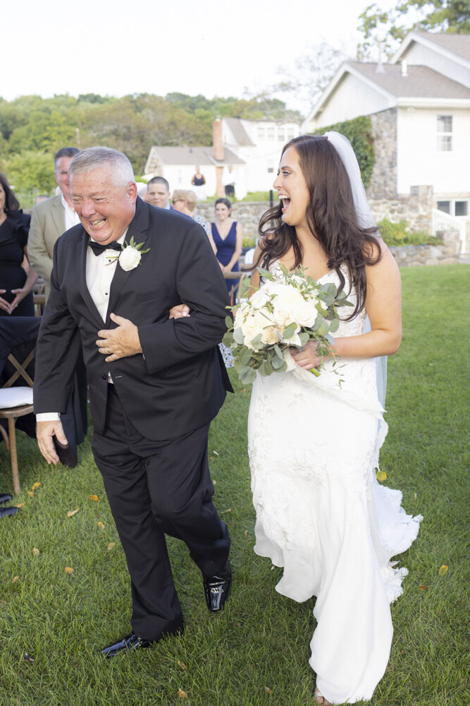 bride and gather laughing as they walk down the aisle at ceremony -candlelight farms inn wedding