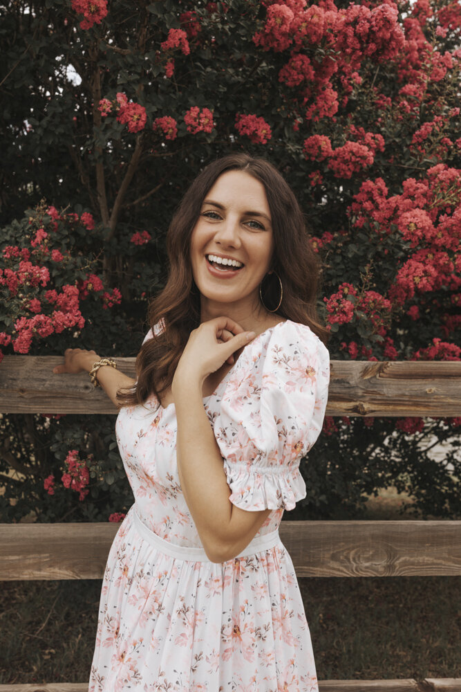 woman smiling in a pink and white floral dress