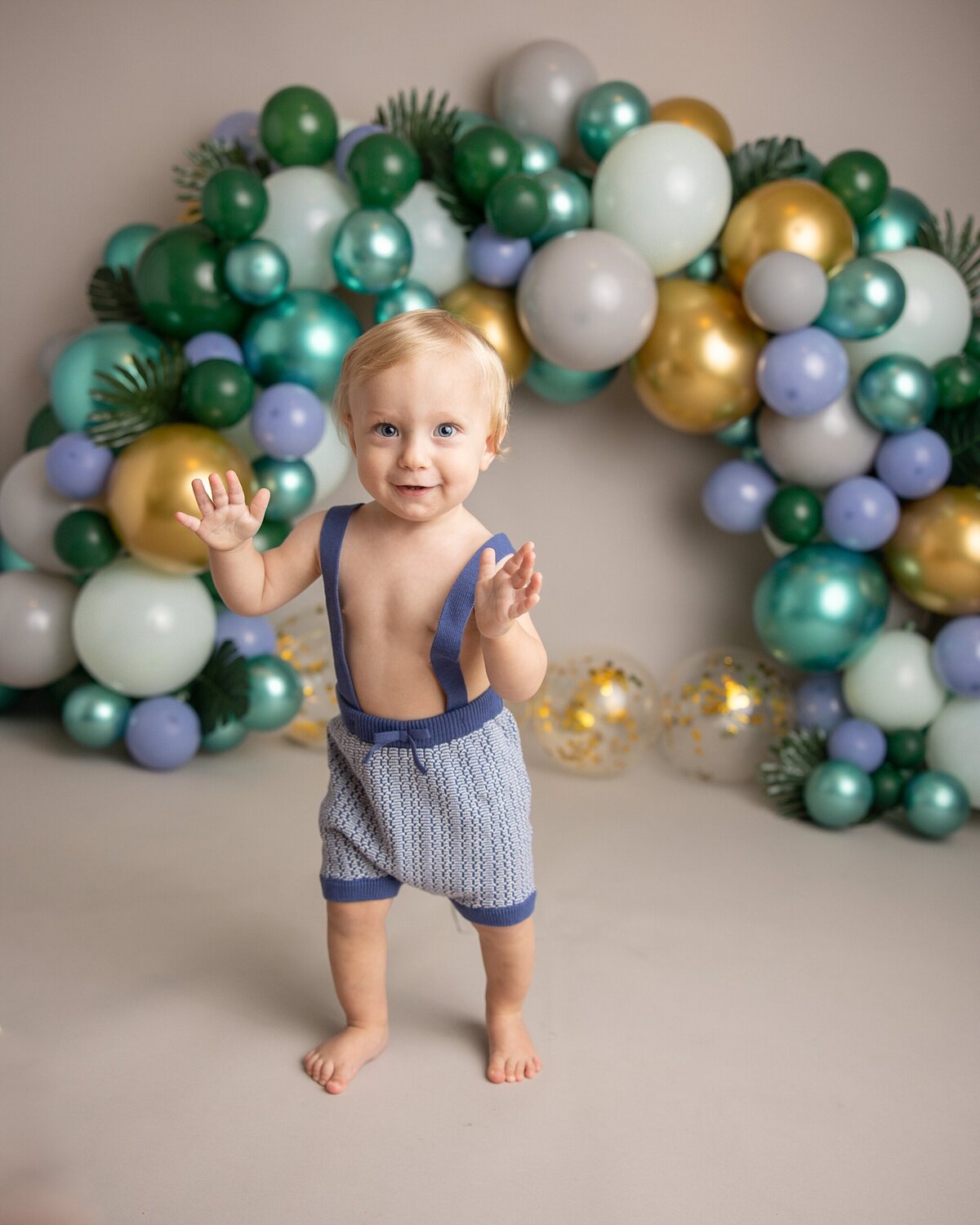 baby boy showing off that he can stand and walk around  for first birthday pictures in PDX photography studio