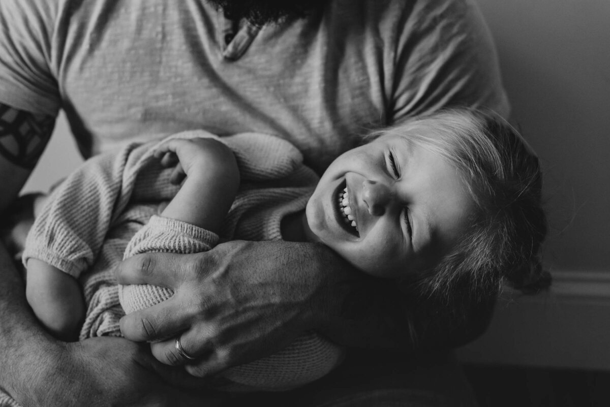 Child Laughs in Father's arms, black and white family photography