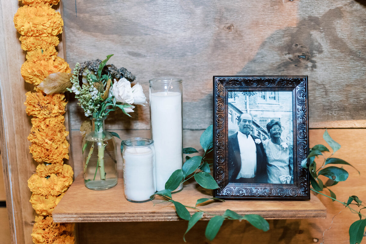 Framed photograph, candles and greenery displayed on a wooden wedding reception backdrop