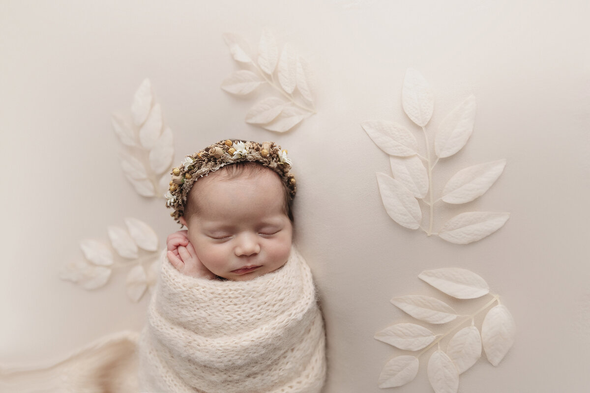 Newborn studio located in Pittsburgh poses newborn baby girl with cream flowers.