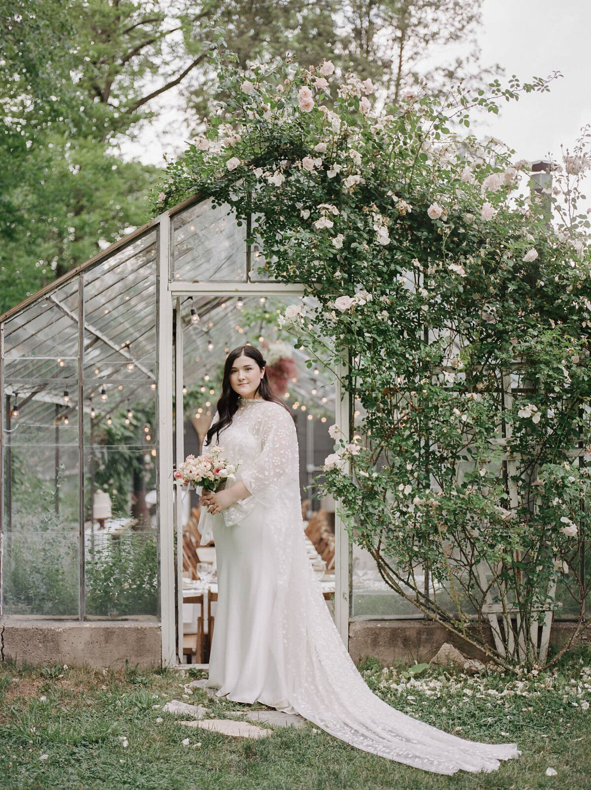 bride in bridal cape at glass greenhouse wedding venue, garden wedding venue in west Michigan